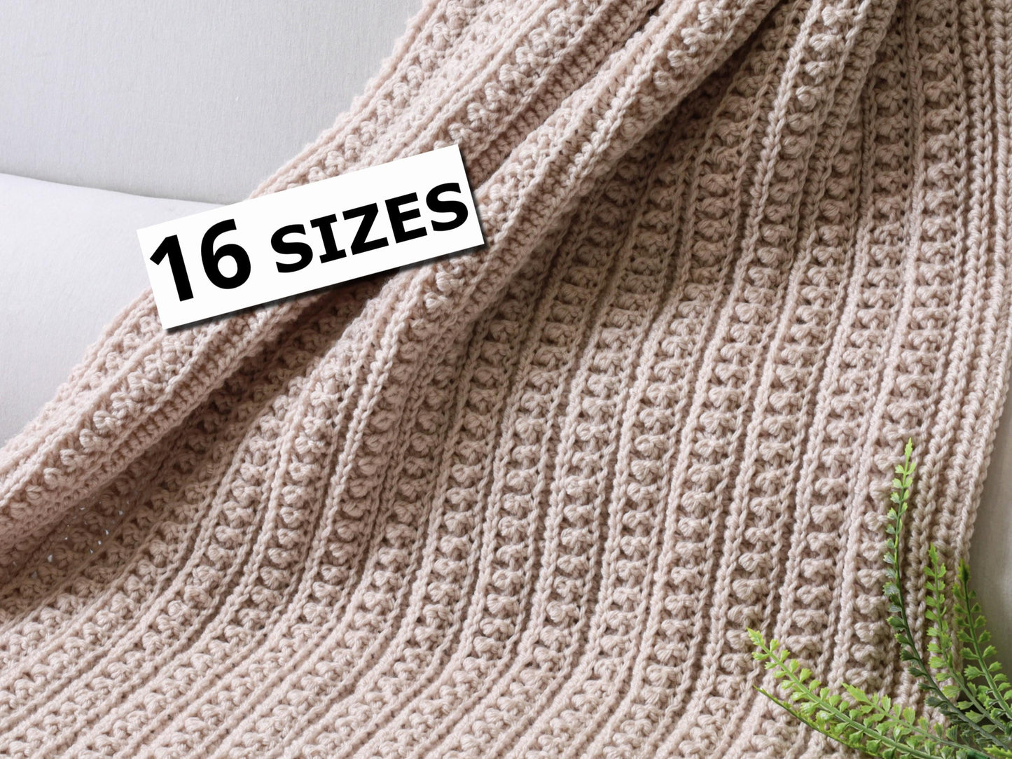 May include: A light beige crocheted blanket featuring a repeating vertical ribbed texture with small raised bobble stitches. A white rectangular label with the black text 16 SIZES is positioned on the upper left side of the fabric.