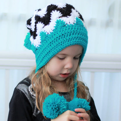 May include: A turquoise crocheted hat with black and white zig-zag pattern and pom-poms. The hat has ear flaps and is worn by a child.