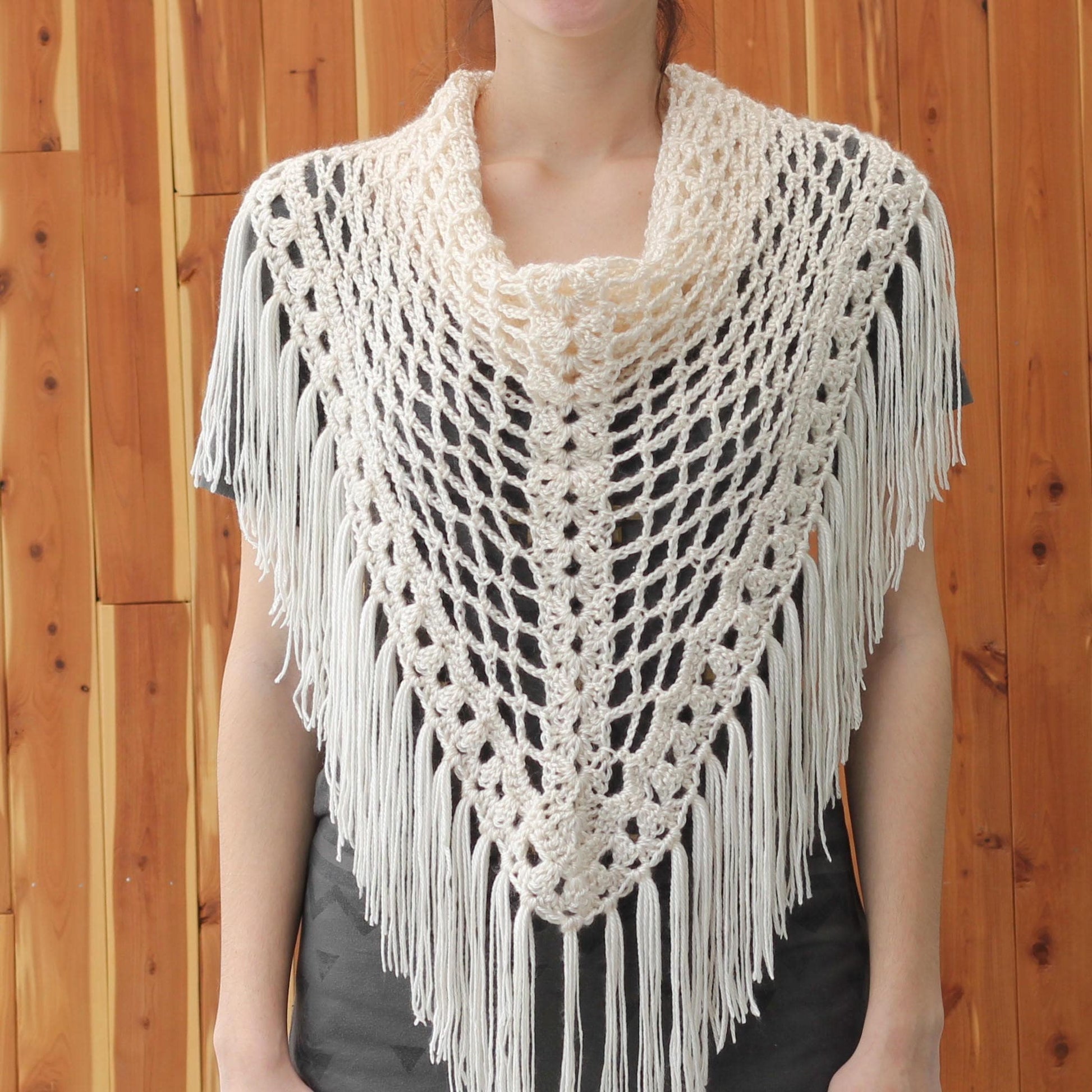 May include: A white crochet shawl with a fringe border. The shawl is made with a delicate openwork pattern.