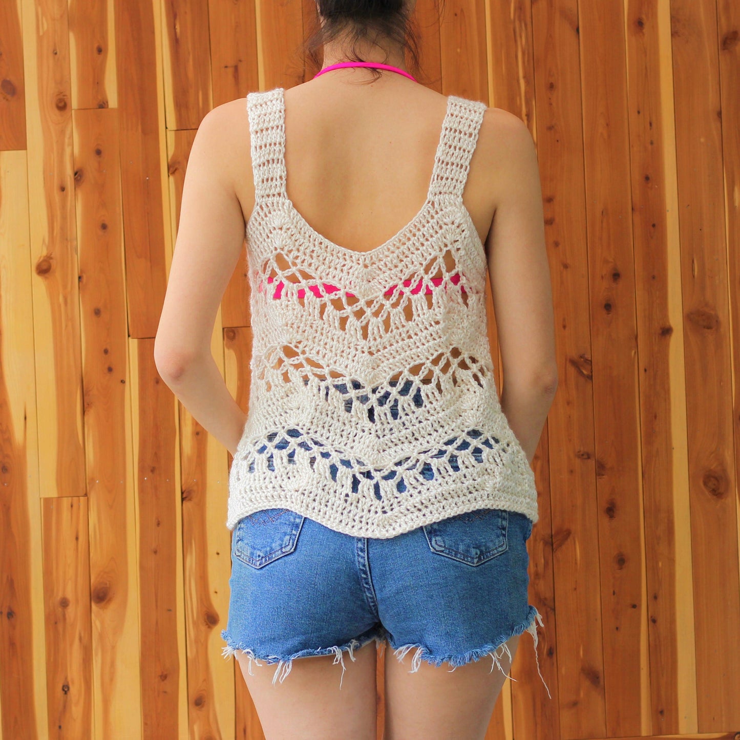 May include: A white crochet tank top with a delicate openwork design. The tank top has a V-shaped back and a relaxed fit.