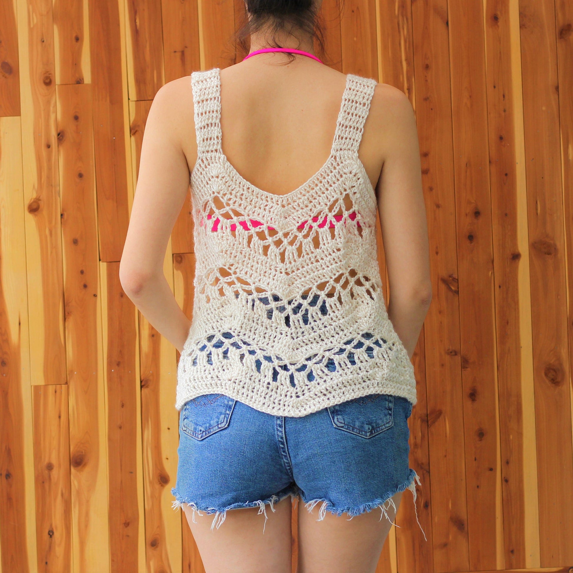 May include: A white crochet tank top with a delicate openwork design. The tank top has a V-shaped back and a relaxed fit.
