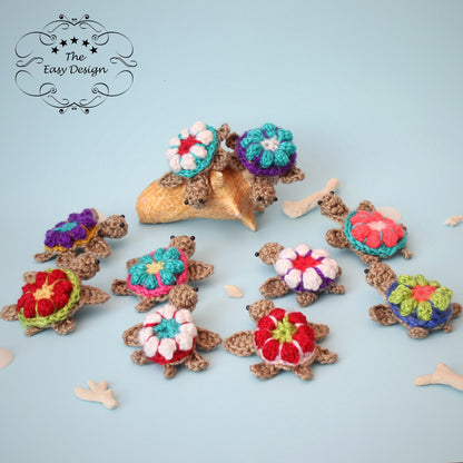 May include: Nine crocheted turtle ornaments with colorful flower designs on their shells. The turtles are arranged on a light blue background.