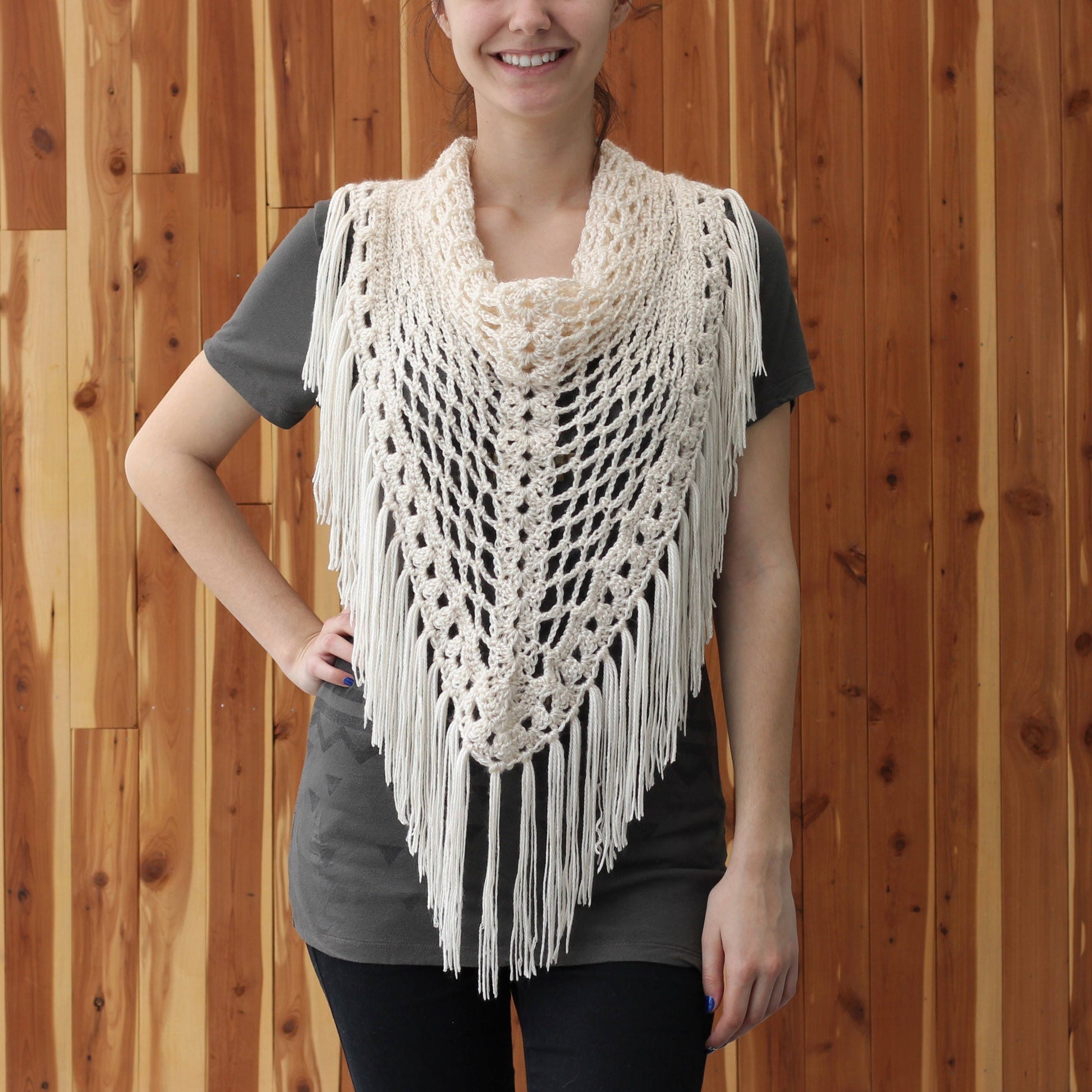 May include: A white crocheted shawl with fringe. The shawl is triangular in shape and has a delicate openwork pattern.