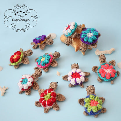 May include: Nine crocheted sea turtle ornaments with colorful flower designs. The turtles are brown with black eyes and are arranged on a light blue background.