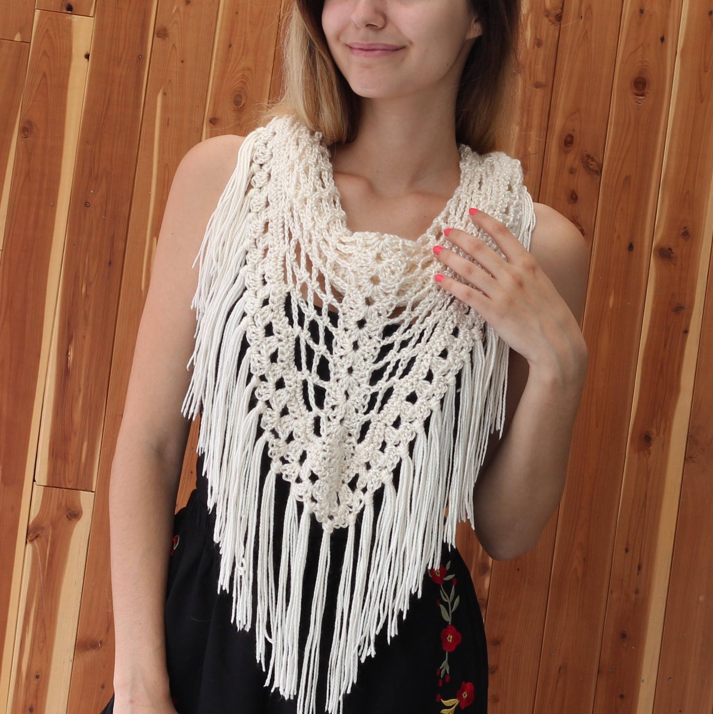 May include: White crochet shawl with fringe. The shawl is crocheted in a delicate pattern and has a scalloped edge. The fringe is long and flowing.
