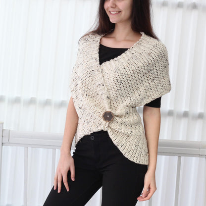 May include: A white crocheted shawl with a brown button closure. The shawl is worn over a black shirt and black pants.