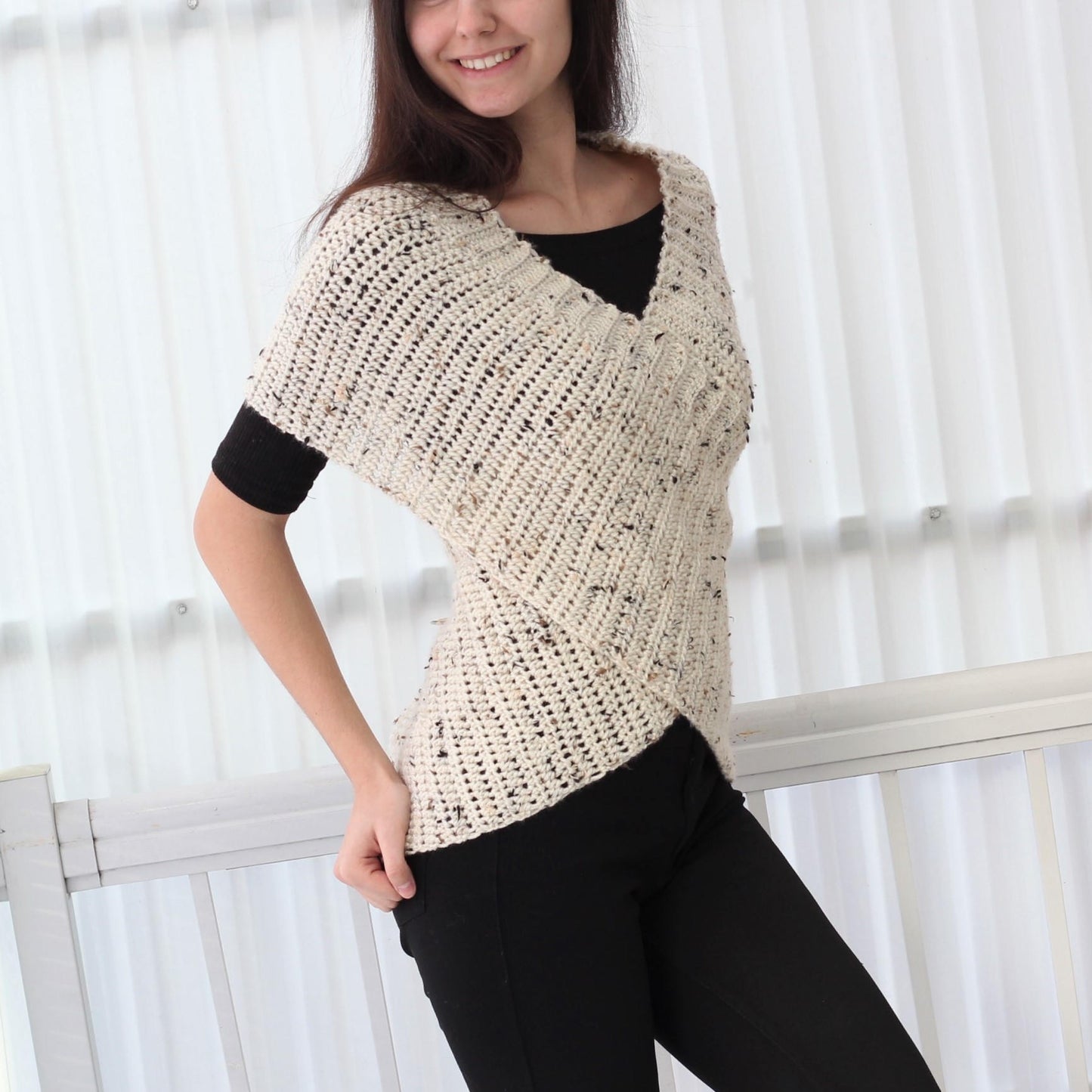 May include: A white crocheted top with a V-neck and a criss-cross design in the front. The top has a speckled pattern and short sleeves.