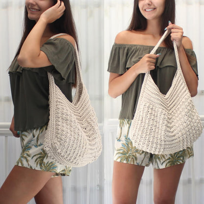 May include: Cream-colored, hand-crocheted tote bag with a wide, open top and long strap. The bag features a textured stitch pattern and a V-shaped design at the top. The bag is shown in a lifestyle shot.