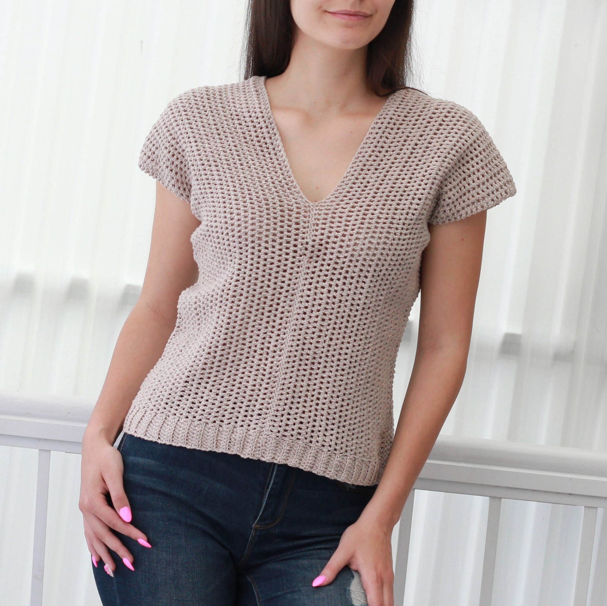 May include: A beige crochet top with a V-neck and short sleeves.