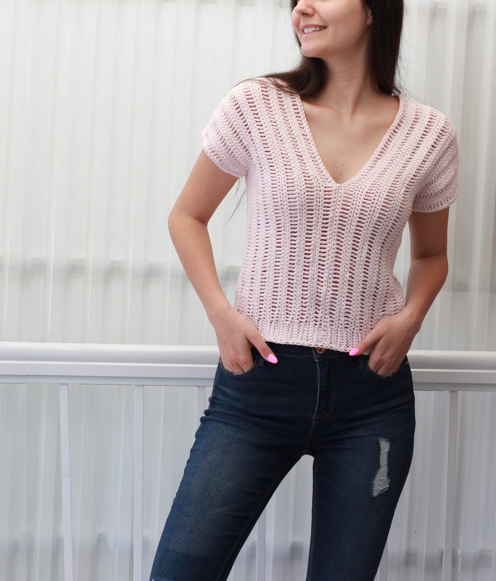 May include: A pink crochet top with a V-neck and short sleeves. The top is made with a loose, open stitch pattern.