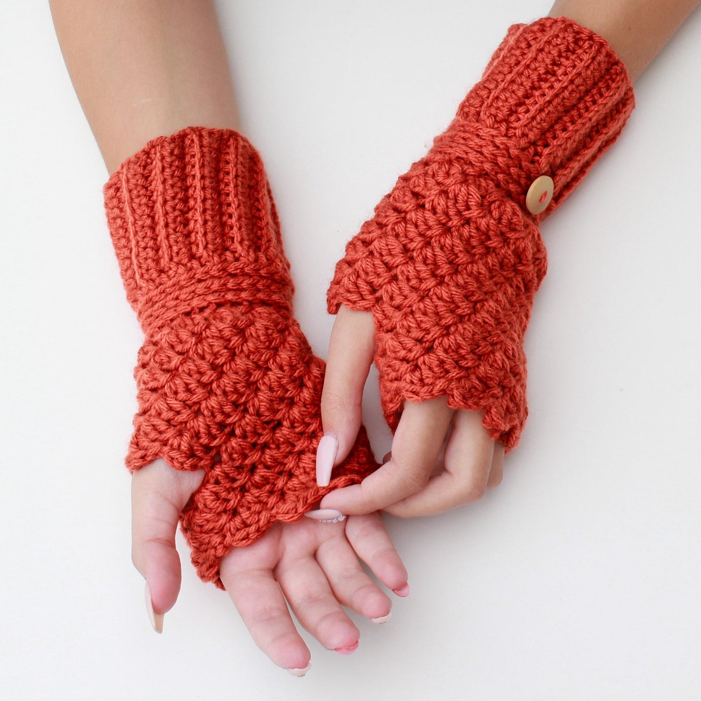 May include: A pair of orange crocheted fingerless gloves with a button on one glove.