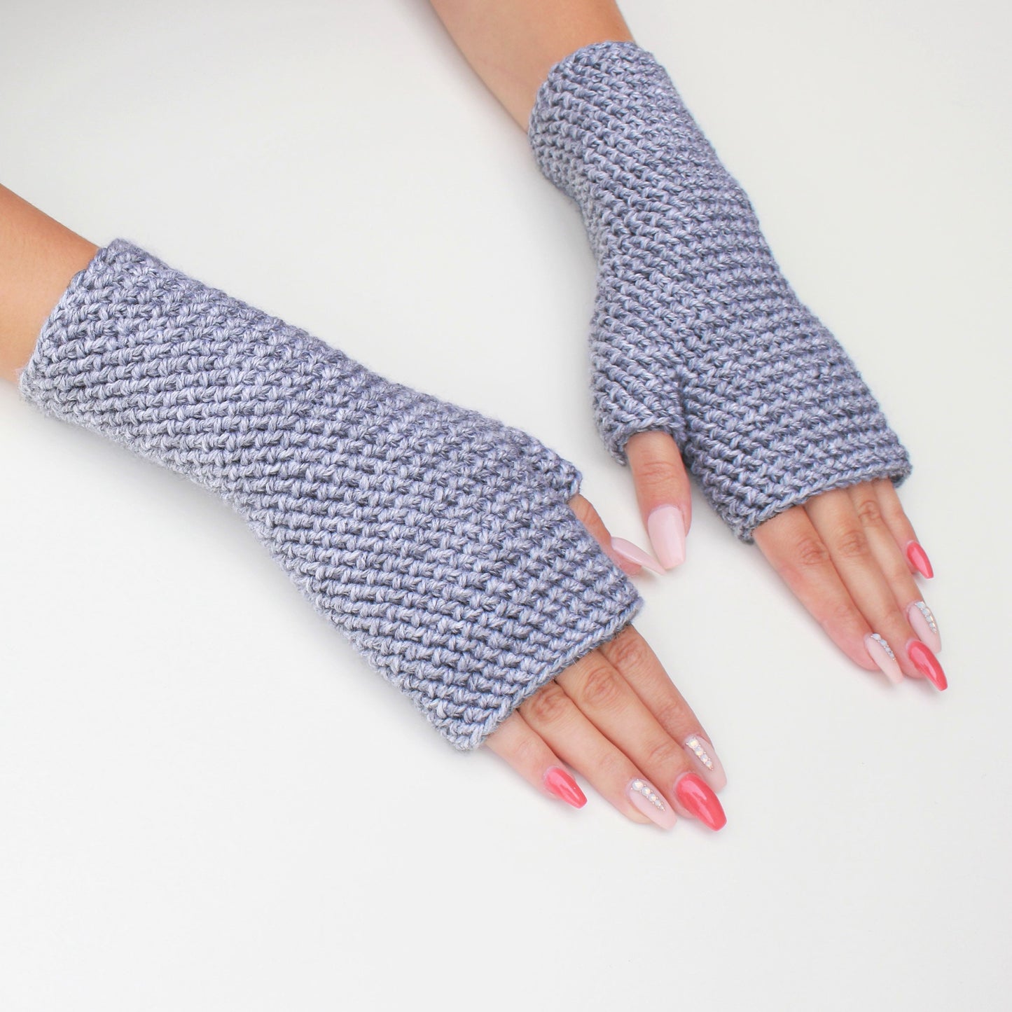 May include: A pair of gray fingerless gloves made of a textured knit fabric.