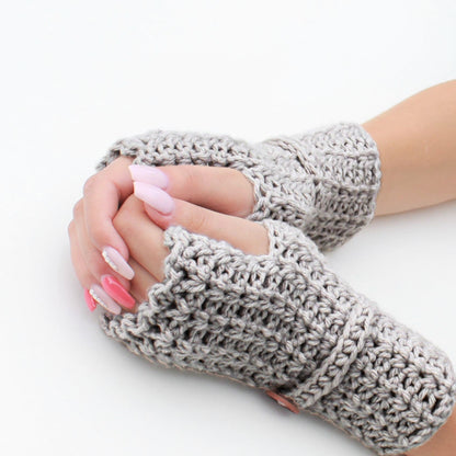 May include: A pair of gray fingerless gloves with a crocheted texture. The gloves are worn on a person's hands, with the fingers exposed.