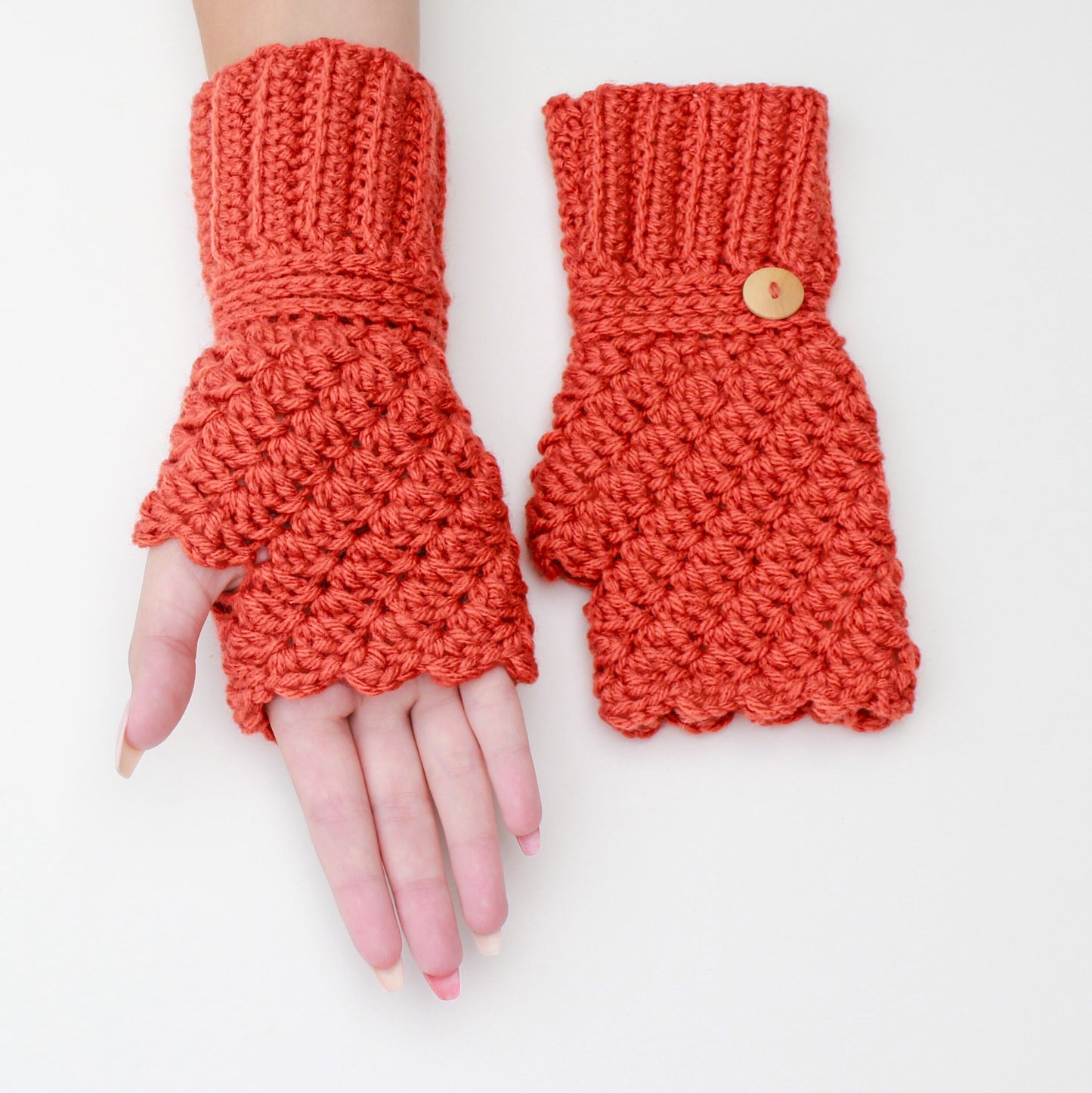 May include: A pair of orange crocheted fingerless gloves with a button on one glove.