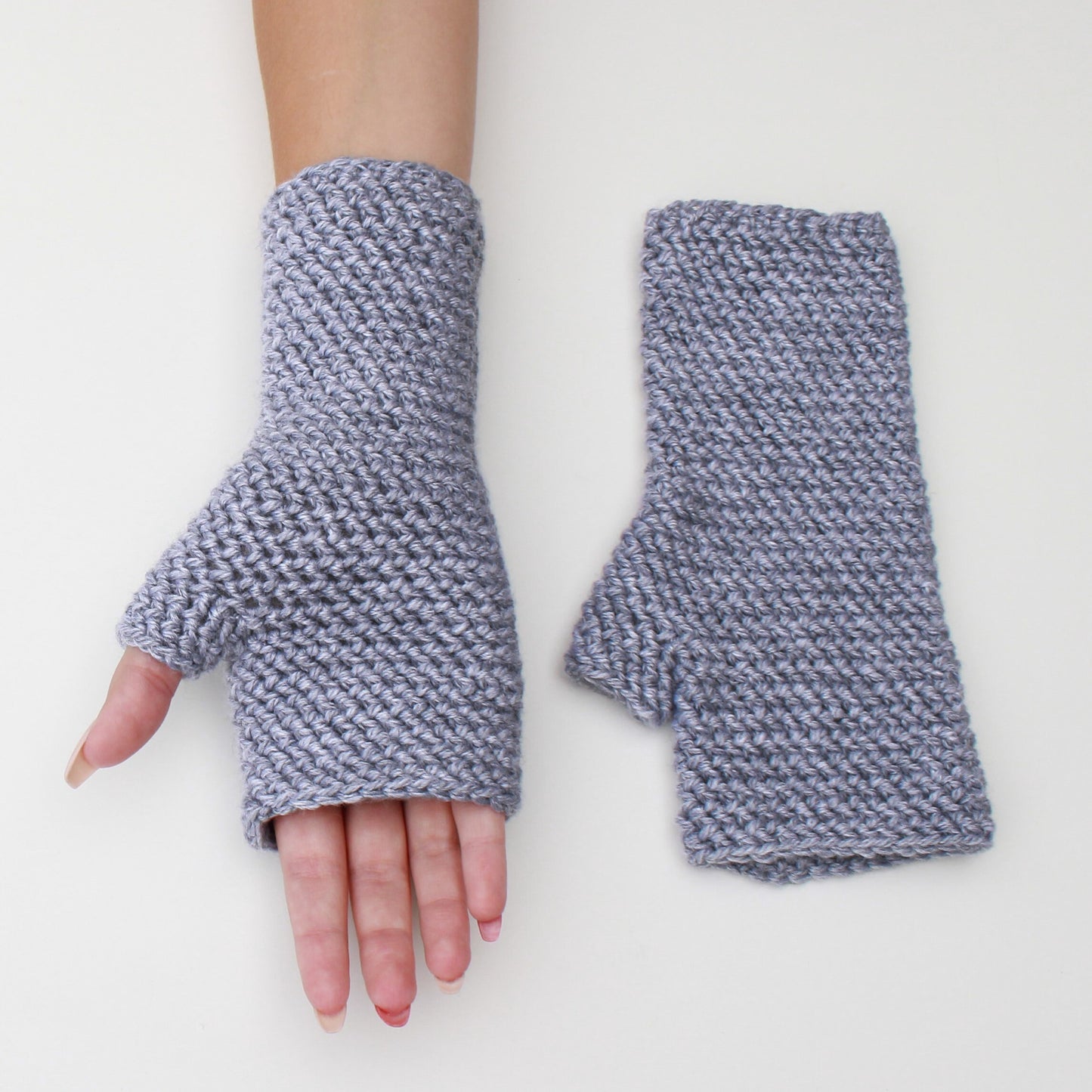 May include: A pair of gray fingerless gloves made of a textured knit fabric. The gloves are shown on a white background.