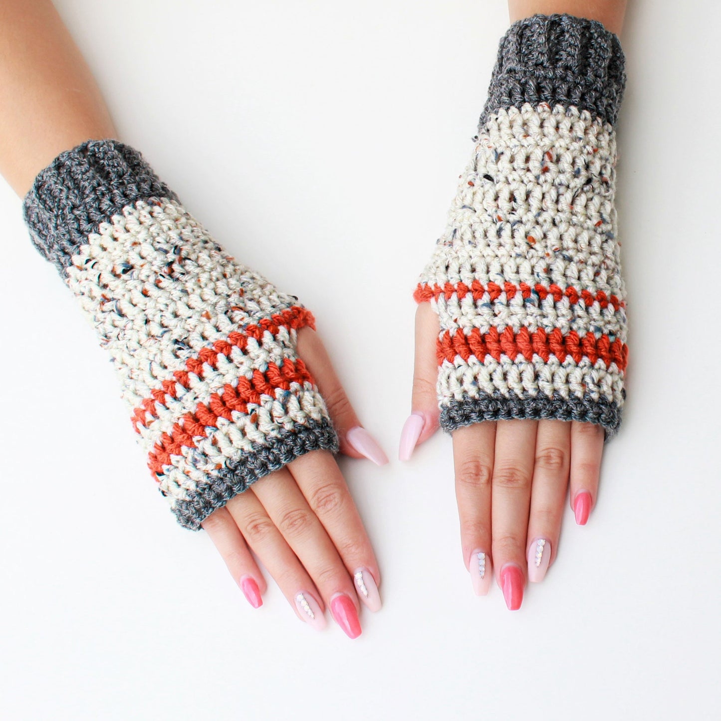 May include: A pair of gray and white fingerless gloves with orange stripes. The gloves are crocheted and have a textured look.