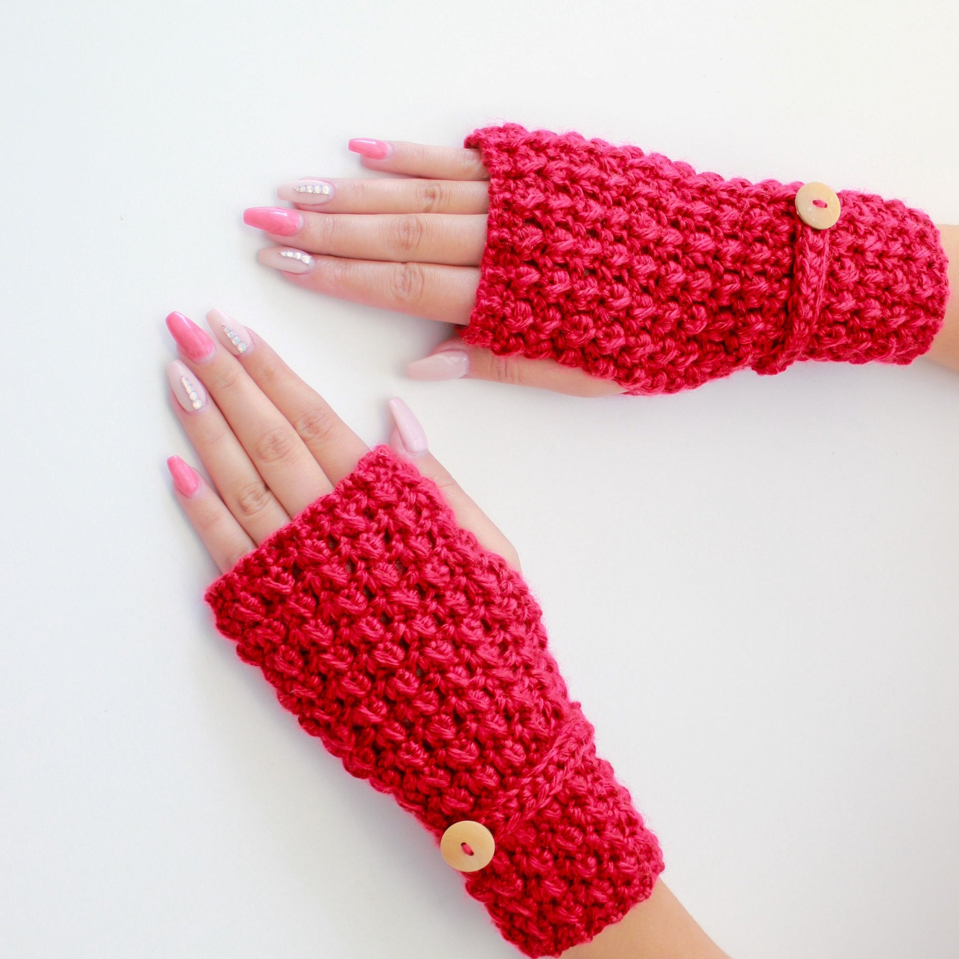 May include: A pair of red fingerless gloves with a button detail. The gloves are made of a crocheted fabric.