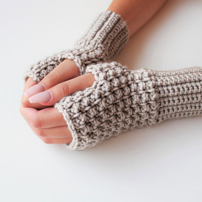 May include: A pair of beige fingerless gloves made of crocheted yarn. The gloves are shown on a white background.
