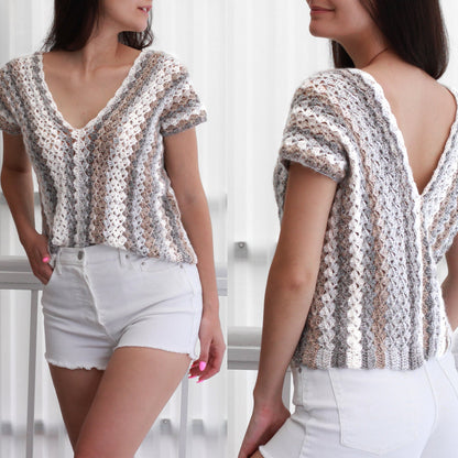 May include: A crocheted top with a v-neck and short sleeves. The top is made with a white, gray, and brown yarn and has a striped pattern. The top is shown on a model wearing white denim shorts.