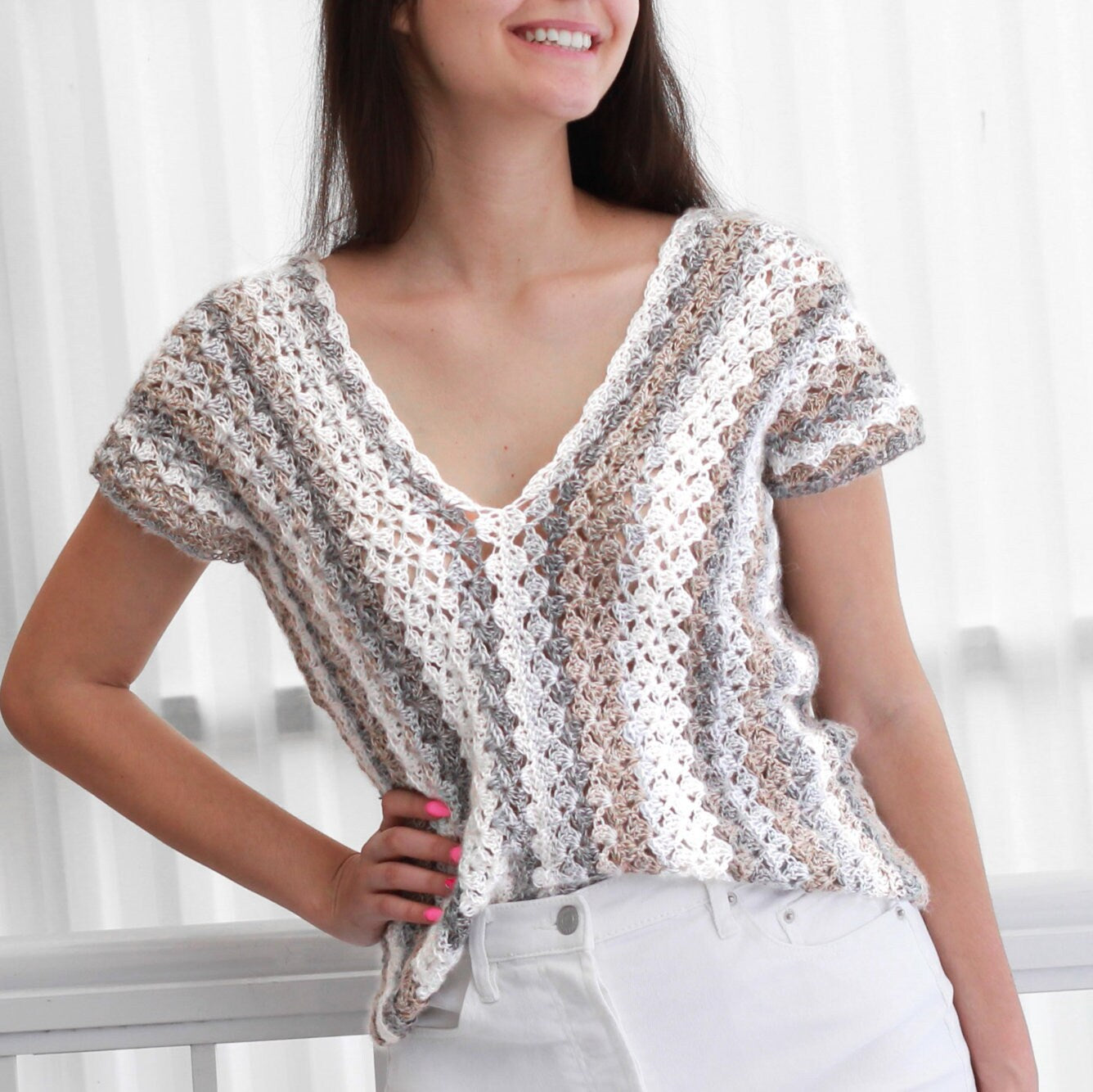 May include: A crocheted top with a V-neck and short sleeves. The top is made with a white, gray, and brown yarn and has a striped pattern.