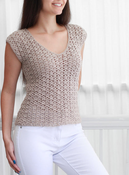 May include: A beige crochet top with a v-neck and short sleeves. The top is made with a delicate open stitch pattern.