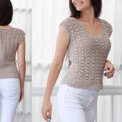 May include: A beige crochet top with a v-neck and short sleeves. The top is made with a delicate stitch pattern and is worn with white pants.