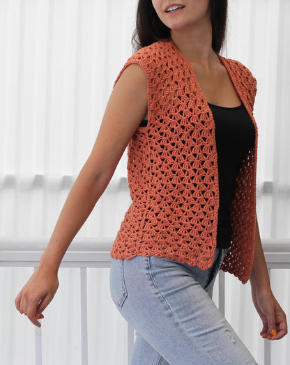 May include: A crocheted sleeveless vest in a coral color. The vest has a V-neck and a scalloped hem.