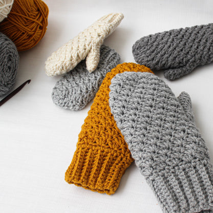 May include: Three pairs of crocheted mittens in different colors: gray, white, and mustard yellow. The mittens are made with a textured stitch and have a simple, classic design.