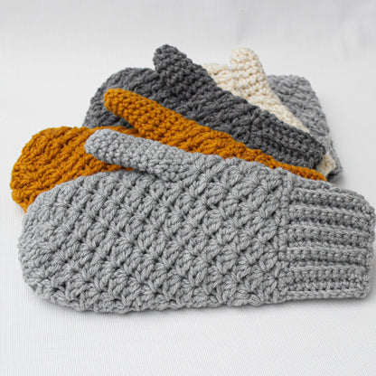 May include: A set of five crocheted mittens in various colors, including gray, mustard yellow, and cream. The mittens are stacked on top of each other, with the gray mitten on the bottom.