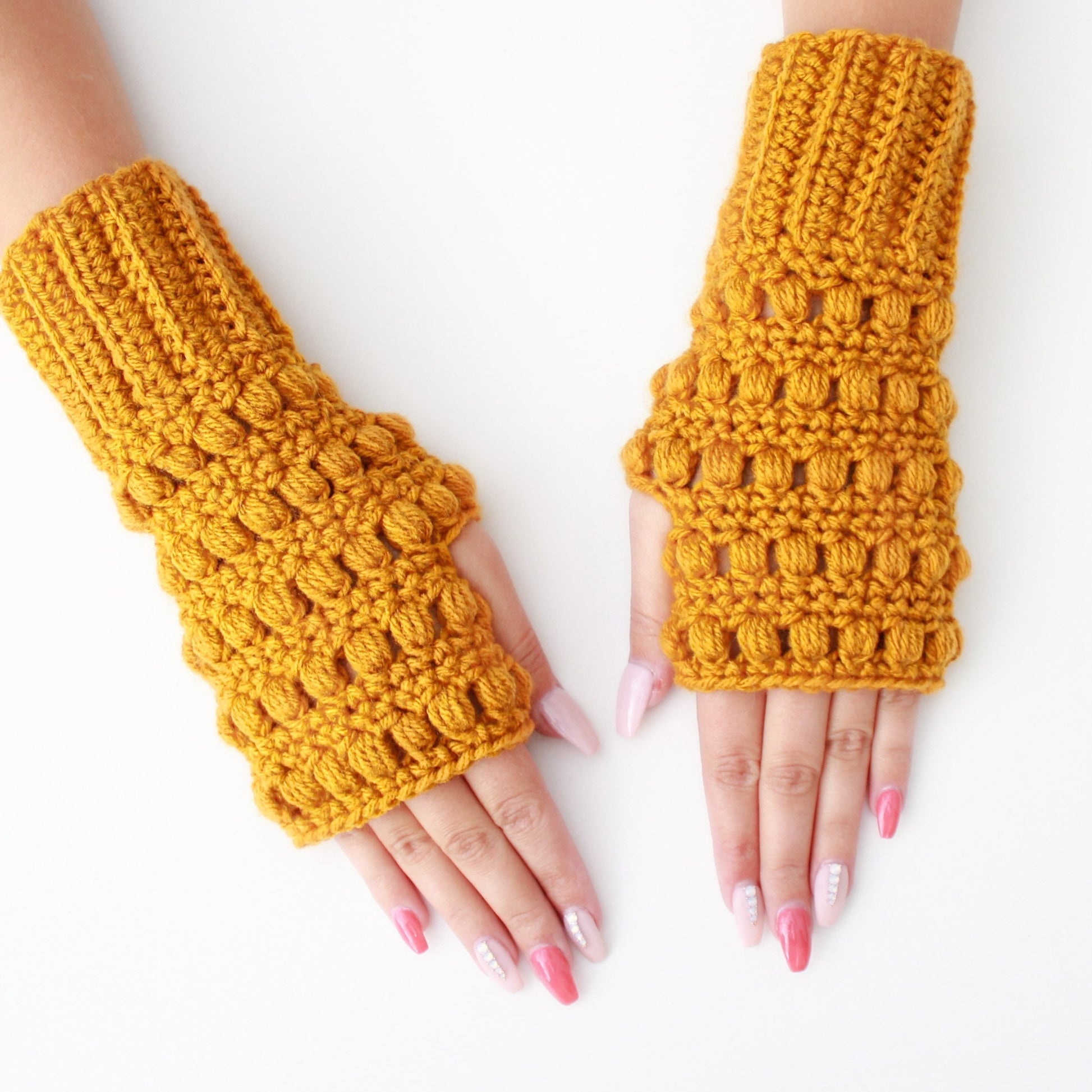 May include: A pair of yellow crocheted fingerless gloves with a textured design. The gloves are made with a chunky yarn and have a loose fit.