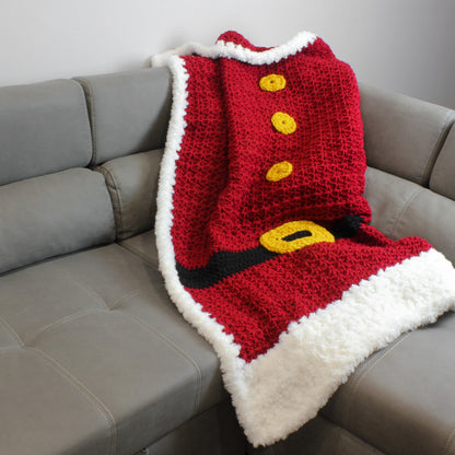 May include: A red and white crocheted blanket with a black belt and yellow buttons, resembling a Santa Claus suit.
