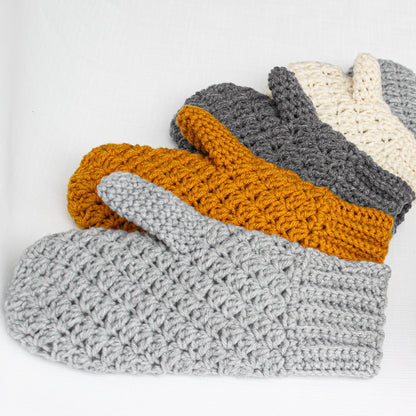 May include: Four crocheted mittens in different colors: gray, mustard yellow, and cream. The mittens are stacked on top of each other.