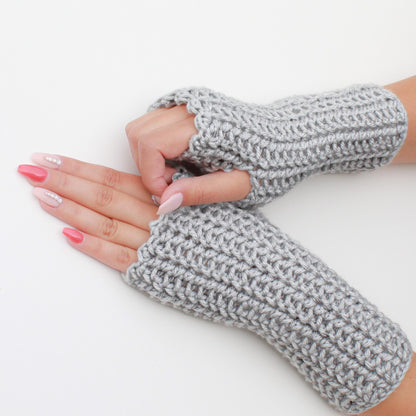 May include: A pair of gray fingerless gloves made of crocheted yarn. The gloves are shown on a person's hands.