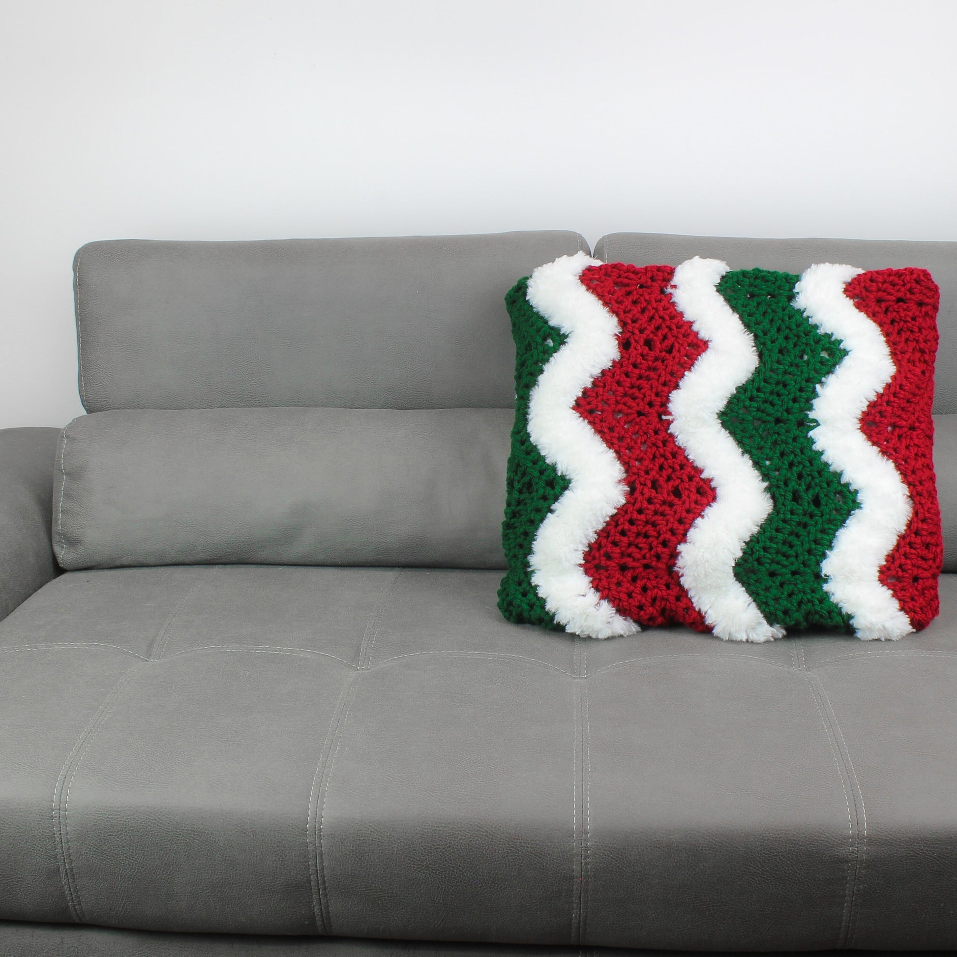 May include: A gray couch with a red, white, and green crocheted pillow with a chevron pattern.