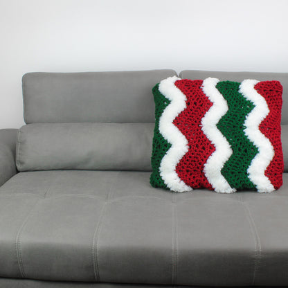 May include: A gray couch with a red, white, and green crocheted pillow with a chevron pattern.