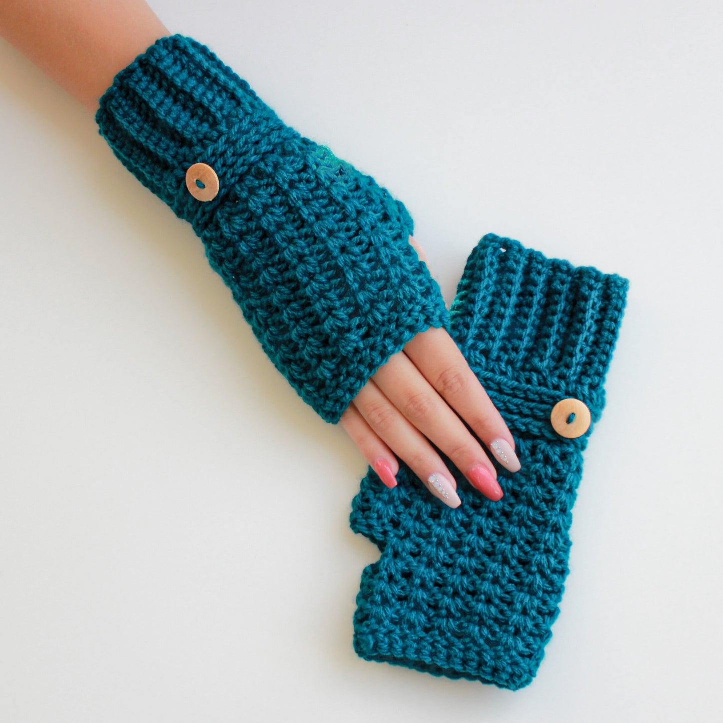 May include: A pair of teal blue crocheted fingerless gloves with wooden button closures.