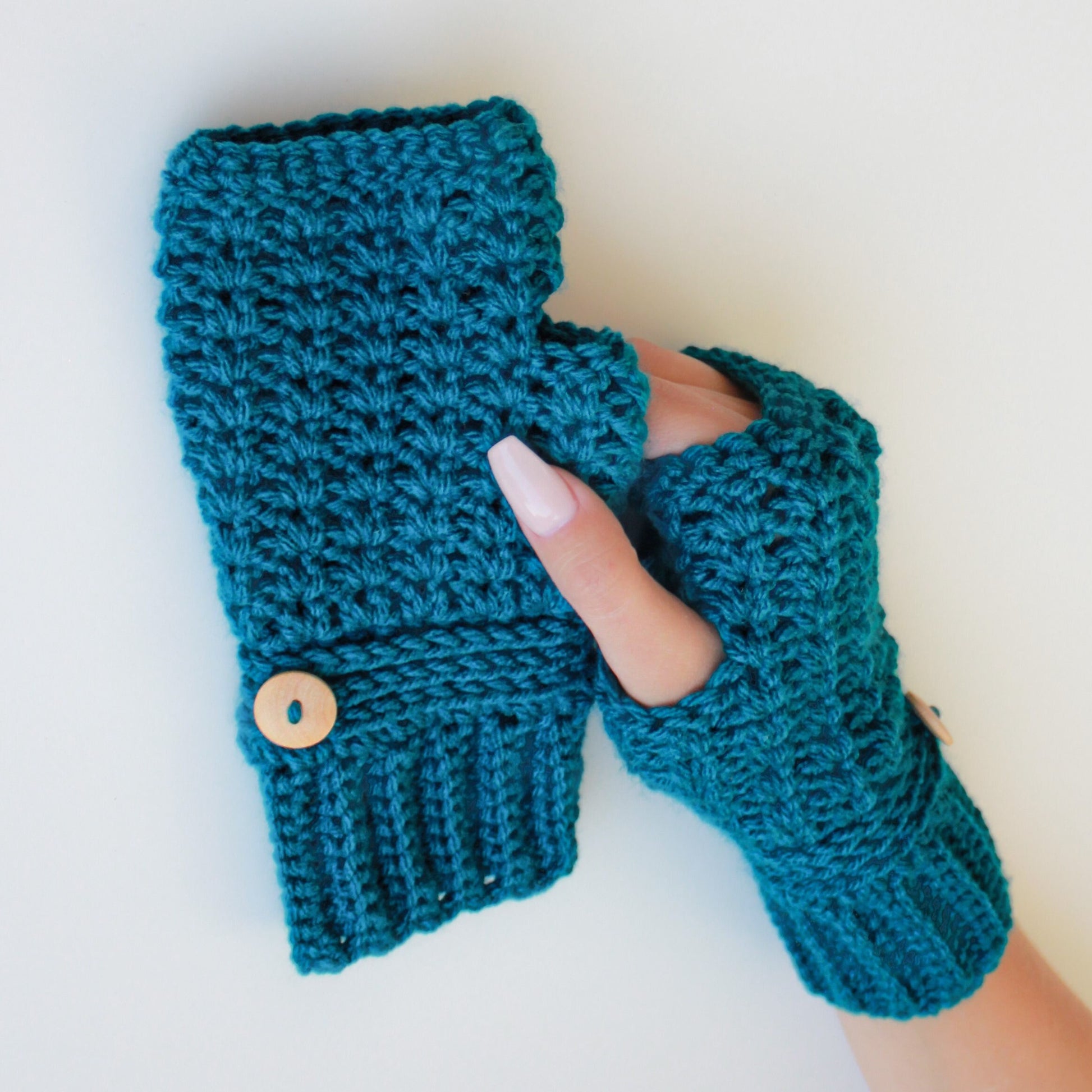 May include: Teal blue crocheted fingerless gloves with a wooden button on the wrist.