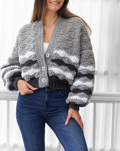 May include: A gray and white striped cardigan with a button closure. The cardigan has a cropped length and long sleeves.