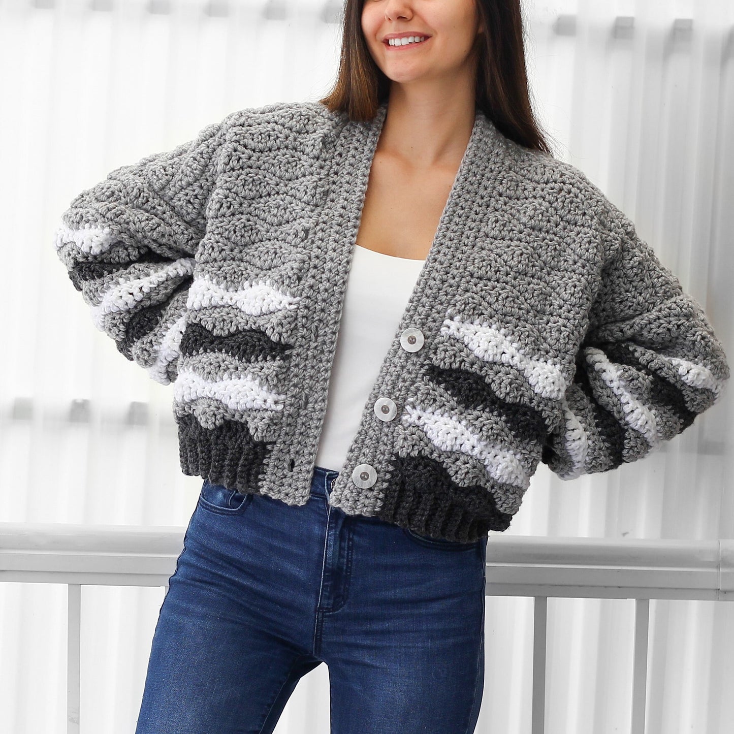 May include: A gray, white, and black striped cardigan with a button closure. The cardigan has a relaxed fit and a cropped length.
