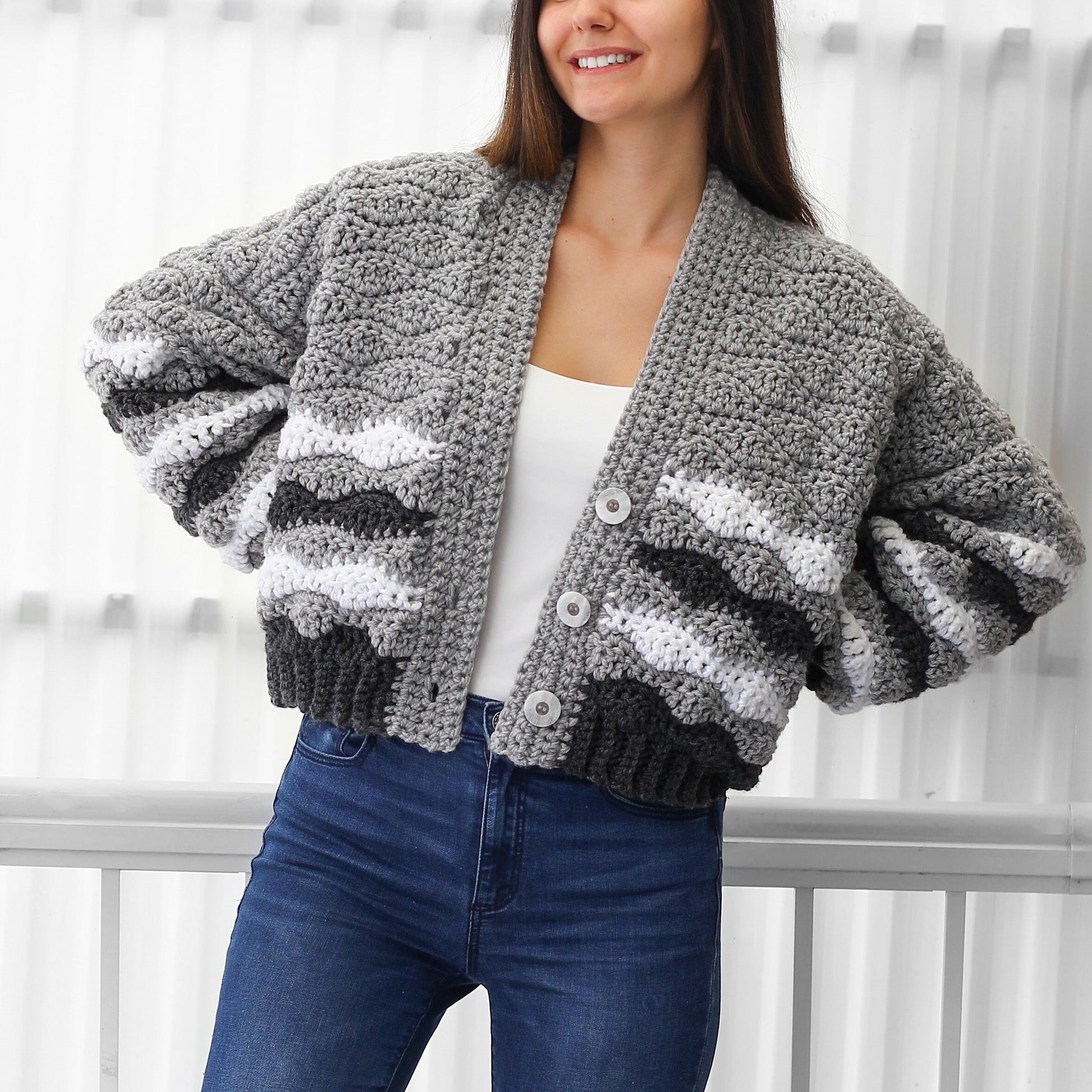 May include: A gray, white, and black striped cardigan with a button closure. The cardigan has a relaxed fit and a cropped length.