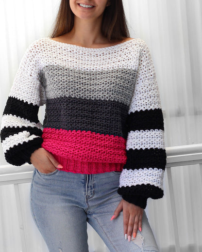 May include: A striped crochet sweater with a white, gray, black, and pink color scheme. The sweater has a loose fit and long sleeves.
