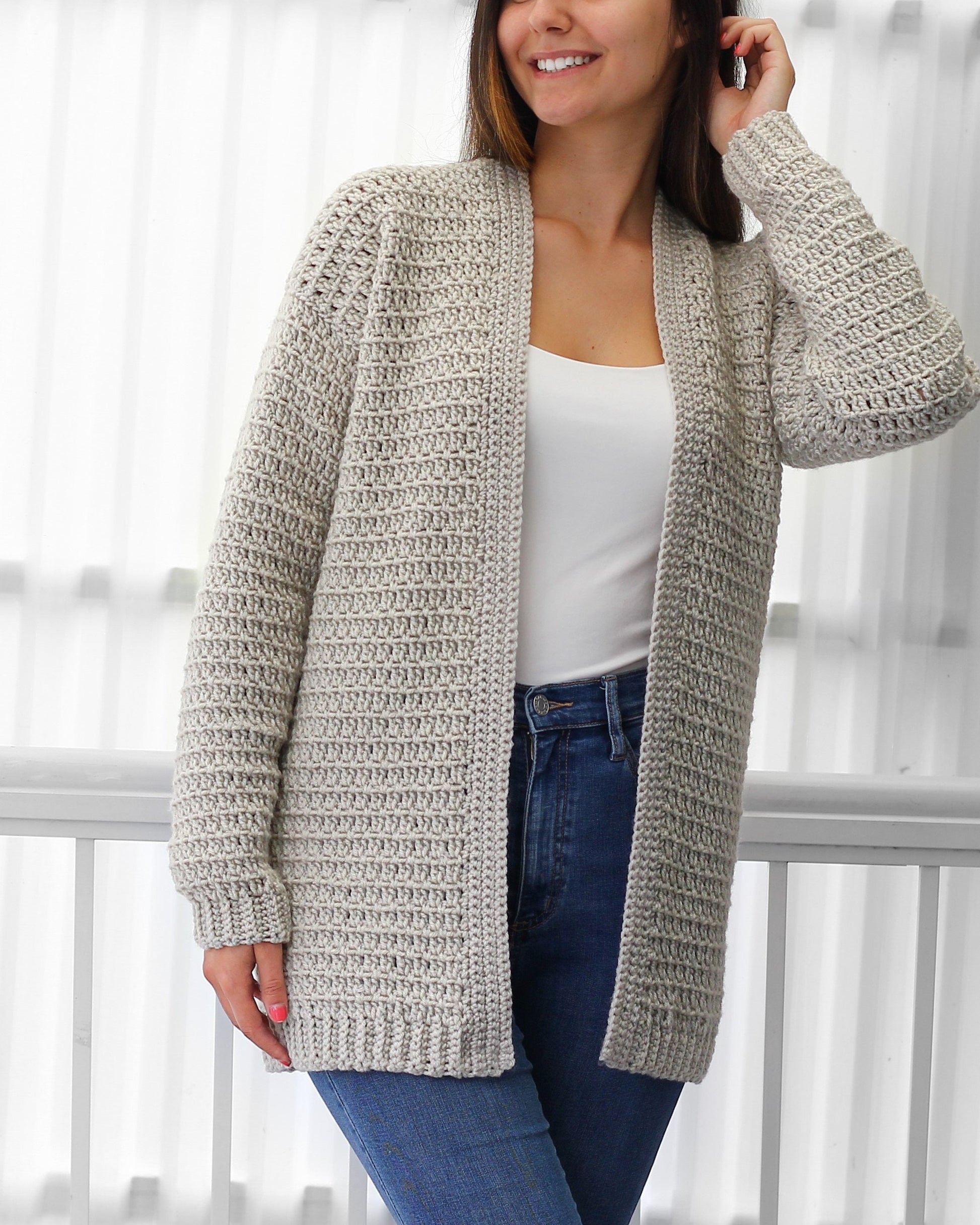 May include: A light gray crocheted cardigan with a long open front and long sleeves.