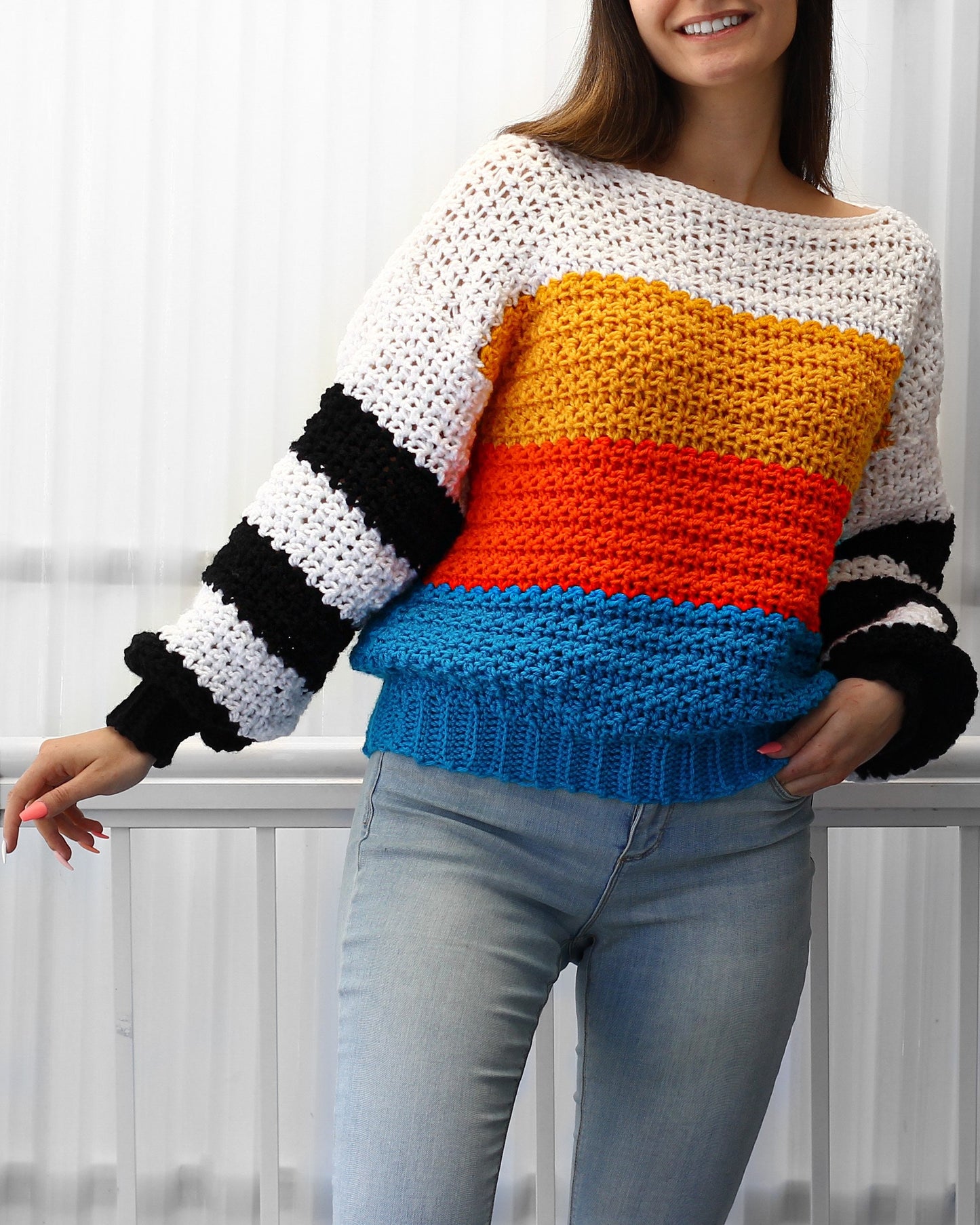 May include: A colorful striped crochet sweater with black and white stripes on the sleeves. The sweater is made in a variety of colors, including white, yellow, orange, and blue.