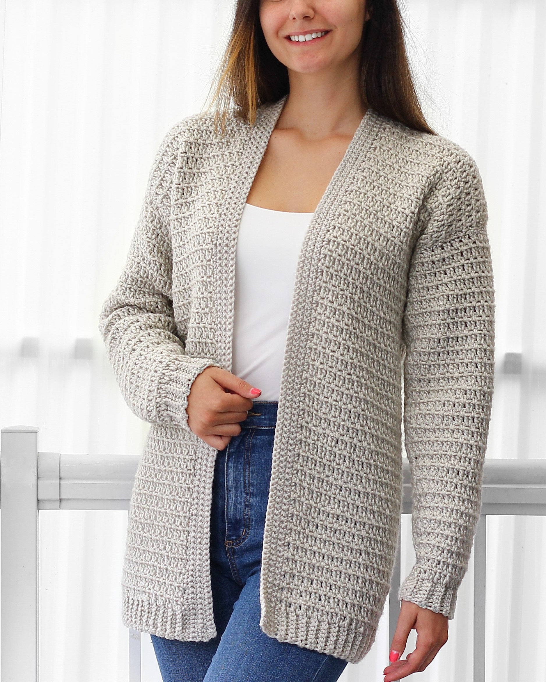 May include: A long-sleeved, open-front cardigan in a light gray and white speckled yarn. The cardigan has a relaxed fit and a simple stitch pattern.
