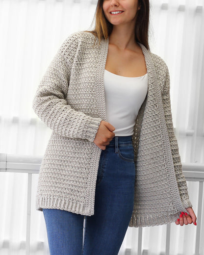 May include: A light gray crocheted cardigan with a long, open front and long sleeves. The cardigan is made with a textured stitch pattern.
