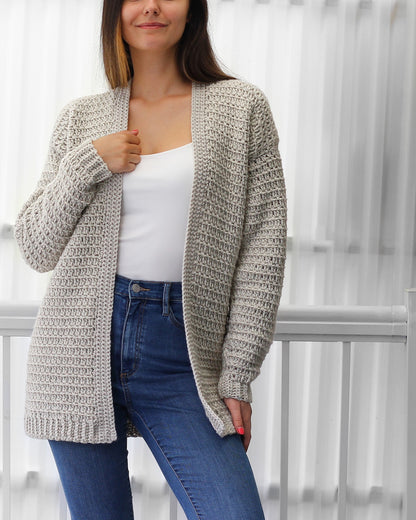 May include: A light gray cardigan with a long, open front and long sleeves. The cardigan is made of a soft, textured yarn and has a relaxed fit.