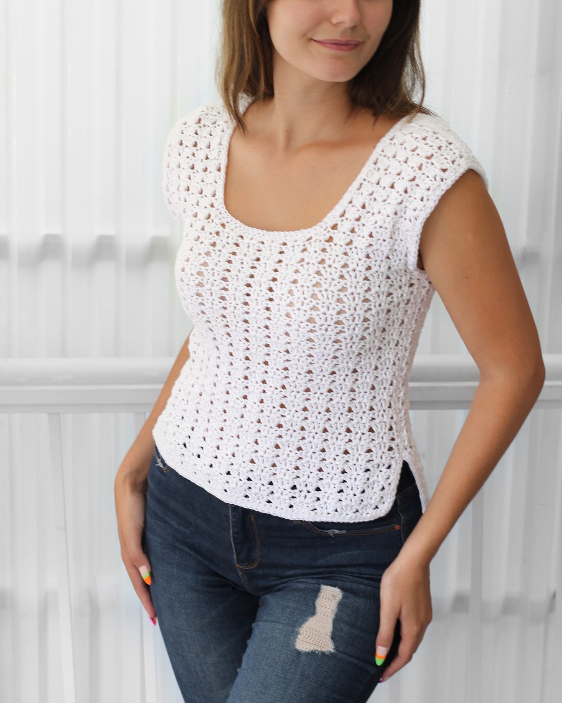 May include: White crochet top with a scoop neck and short sleeves. The top has a loose fit and a slightly longer length in the back.