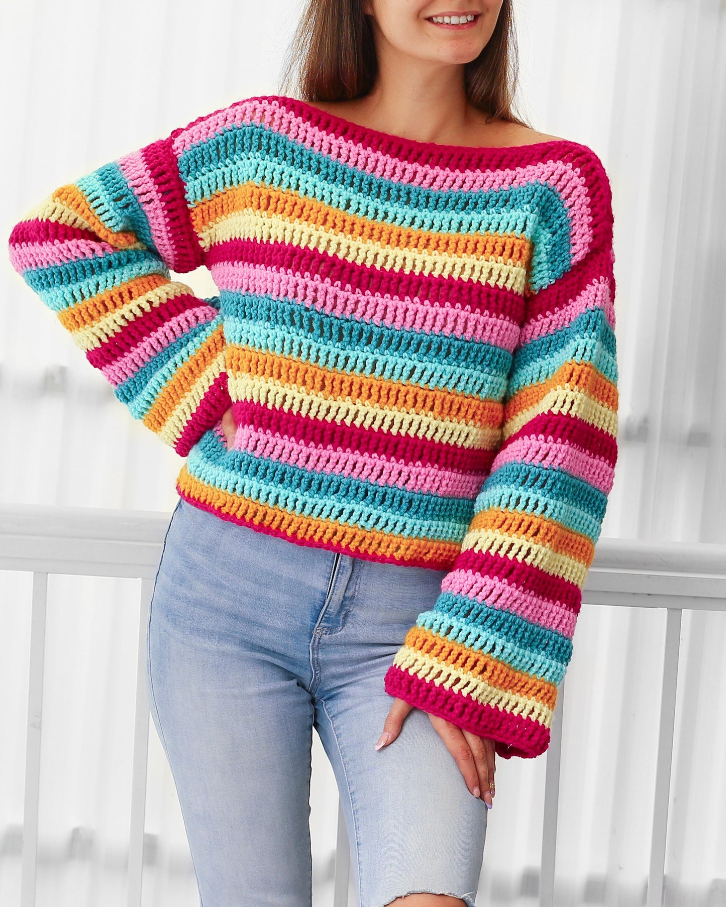May include: A colorful striped crochet sweater with long sleeves. The sweater is made with a variety of bright colors, including pink, orange, yellow, and blue.