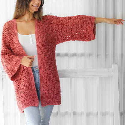 May include: A long, loose-fitting, crocheted cardigan in a dusty rose color. The cardigan has a wide, open front and long sleeves with a bell shape at the cuffs.