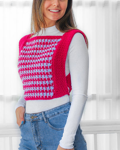 May include: A pink and blue crocheted vest with a houndstooth pattern. The vest is sleeveless and has a square neckline.